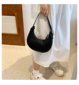 Detail of minimalist black crescent shoulder bag with smooth matte finish and zipper