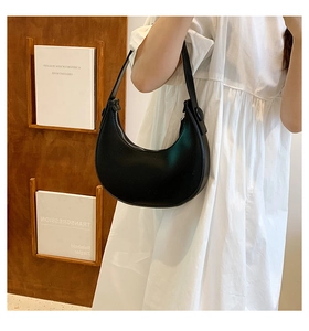 Close-up of a black leather hobo bag worn with a white dress for a stylish daily look