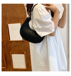 Close-up of a black crescent shoulder bag with smooth matte leather on a model