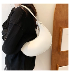 Detailed side view of white crescent leather shoulder bag worn by model