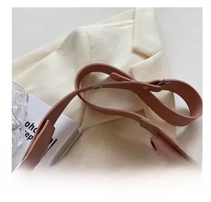 Detail of pink leather handbag showing wide shoulder strap and silver metal buckle