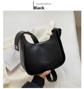 Detail of matte black crescent underarm bag with fashion typography and wide strap