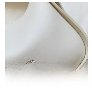 Detail shot of white leather bag showing embossed logo and precise stitching craftsmanship