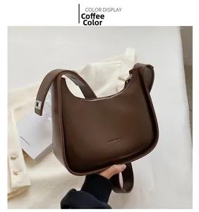 Detail of a brown leather hobo bag with Fashion Bag New York text and wide shoulder strap