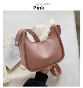 Pink crescent moon shoulder bag featuring a fashion logo and matte leather texture