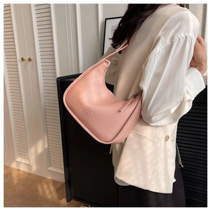 Close-up of pink semi-circle hobo bag worn by model featuring fashion bag lettering