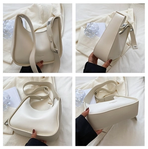 Detail view of cream crescent crossbody bag with adjustable wide strap and silver buckle
