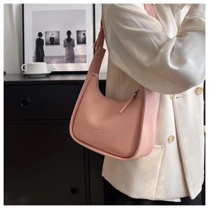 Shoulder view of pink half-moon underarm bag with fashion typography and wide strap