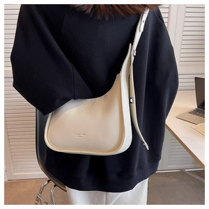 Close-up of a minimalist cream crossbody bag on a model featuring an adjustable strap