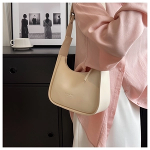 Close-up of cream shoulder bag featuring fashion bag NEW YORK logo and leather texture