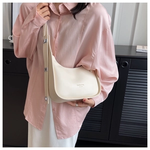 Detail of minimalist beige crescent shoulder bag with embossed lettering and adjustable strap
