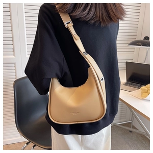 Close-up of beige crescent shoulder bag with adjustable strap and metallic logo detail