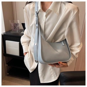 Detail of light blue crescent underarm bag with silver 'fashion bag' print on matte leather