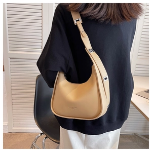 Detail of milk tea color crossbody bag with silver hardware on model's shoulder