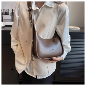 Brown leather hobo bag with fashion bag lettering shown on a shoulder in a modern room