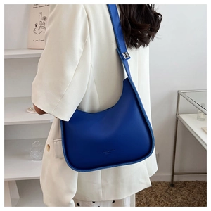 Detail of royal blue crescent shoulder bag featuring smooth PU leather and wide strap