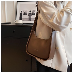 Brown leather hobo bag in half-moon shape styled with a white blazer for workwear