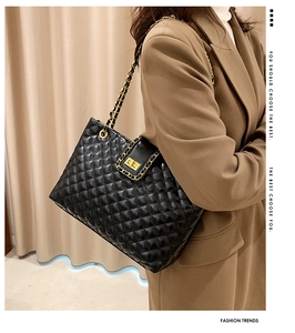 Detail of black quilted leather tote with gold chain strap and metallic square twist lock