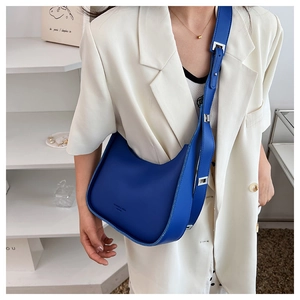Detail of electric blue hobo bag with adjustable strap and silver buckle on white blazer