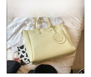Size comparison of beige faux leather tote bag with a round smiley face charm