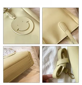 Close-up of yellow tote bag showing fine stitching, smiley pendant, and metal hardware
