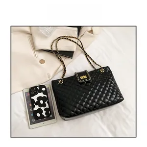 Close-up of black quilted tote bag with gold chain strap and elegant metallic twist lock