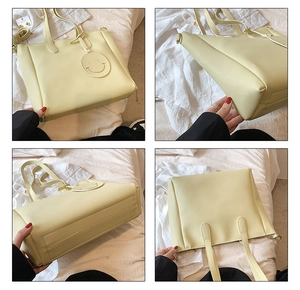 Detail view of large pale yellow PU leather tote bag with iconic smiley face charm