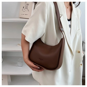 Detail of a dark brown hobo bag with a minimalist crescent design and wide shoulder strap