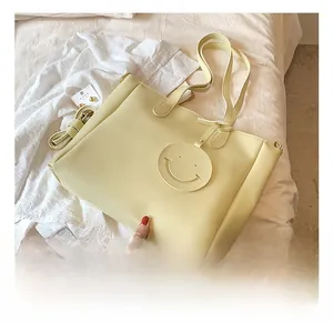Close-up of beige PU leather tote bag featuring a decorative hollow smiley face pendant
