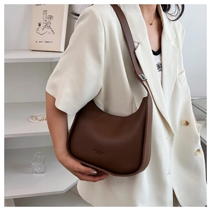 Detail of dark brown leather crescent bag with adjustable buckle strap on female model