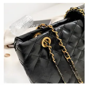 Detail shot of premium gold chain hardware on a quilted black leather tote bag