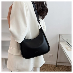 Detail of black crescent shoulder bag featuring silver zipper and wide adjustable strap