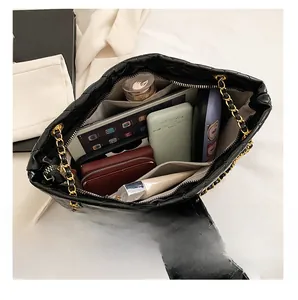 Detailed top view of black quilted tote bag interior with gold chain strap and spacious storage