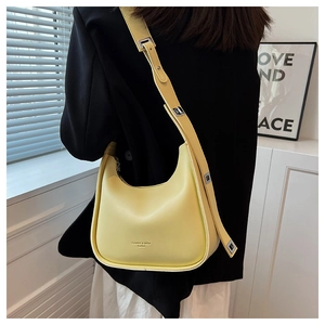 Close-up of yellow crescent leather crossbody bag with adjustable metallic buckle strap