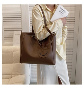 Brown large capacity leather tote bag with a smile charm shown on a model