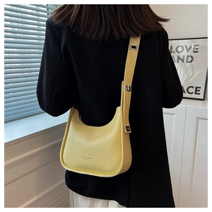 Detail of yellow leather crossbody bag with wide strap and silver buckle on model