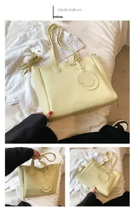 Detail shot of yellow large tote bag with smiley pendant and smooth leather texture