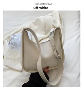 Detail of a creamy white half-moon hobo bag with adjustable strap and brand logo