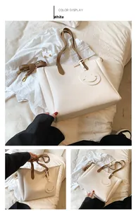 Close-up of white tote bag featuring brown straps and a cute round smiley face charm