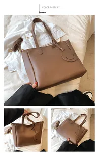 Detail view of large brown PU leather tote bag with smile pendant and adjustable strap