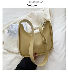 Detail view of yellow crescent shoulder bag with wide strap on a white blazer
