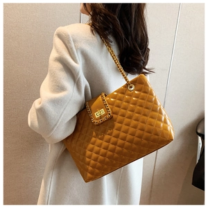 Close-up of yellow quilted tote bag with gold chain strap worn over a white wool coat