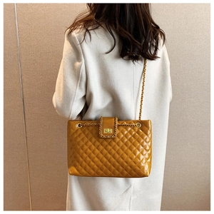 Detailed back view of a ginger quilted leather tote bag on a white wool coat