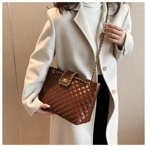Close-up of brown quilted leather bag with golden twist lock and chain strap