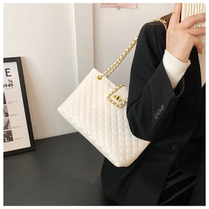 Close-up of white quilted crossbody bag with gold chain strap and metal turn-lock detail