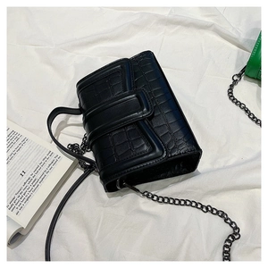 Top view of black crocodile pattern shoulder bag with metal chain on white fabric