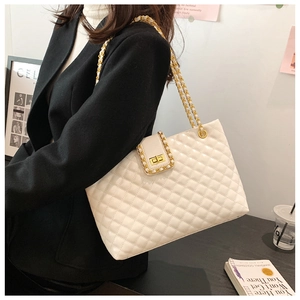 Detail of white quilted tote bag with gold swivel lock and chain strap on shoulder