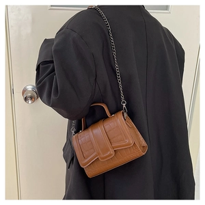 Brown crocodile pattern crossbody bag with chain strap shown on model's shoulder