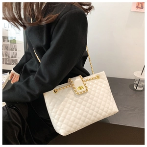 Close-up of cream white quilted crossbody bag with gold chain strap and turn-lock closure