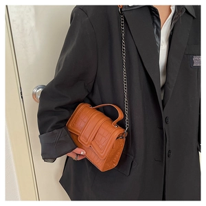 Detail of brown faux crocodile leather bag with silver chain strap and top handle design